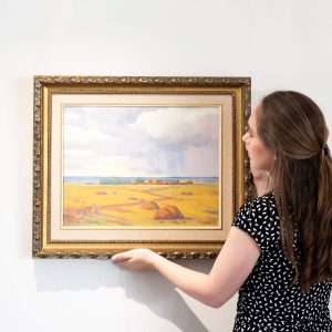 Woman mounting a painting on the wall
